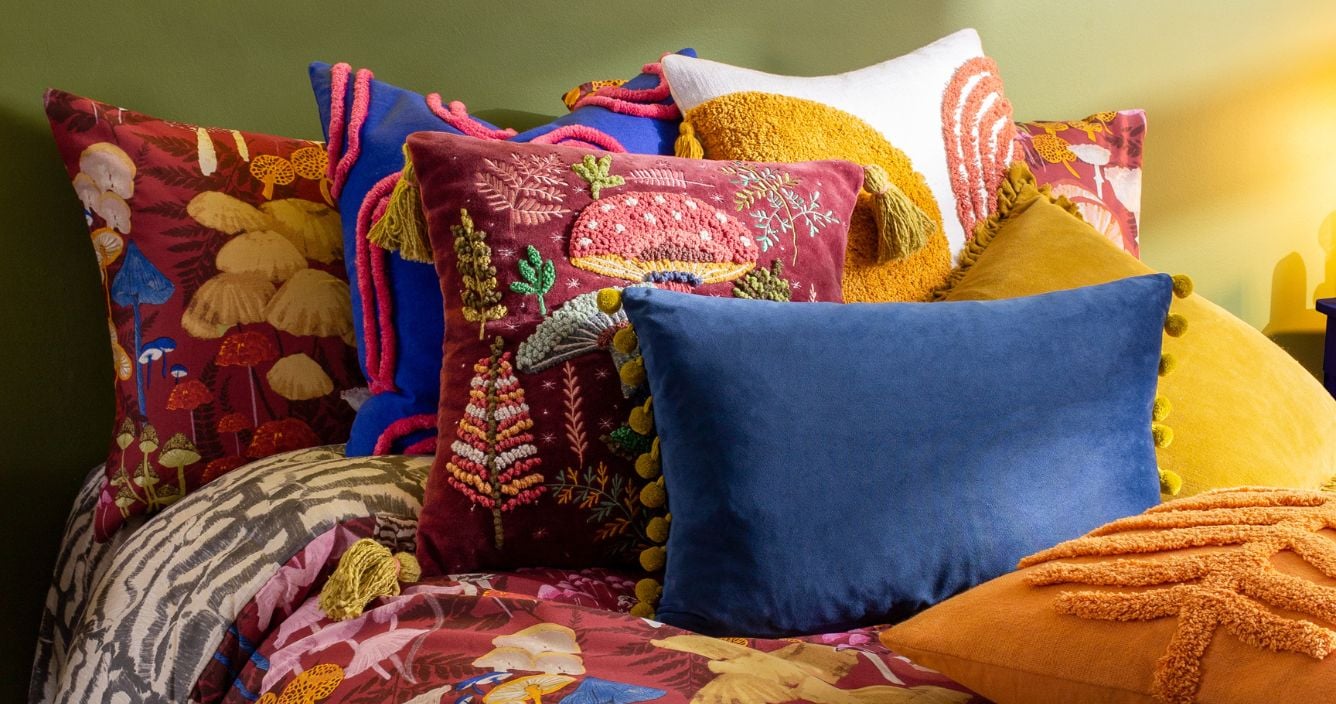 Maximalist bedding in boho colors with cozy pillows and morning light.