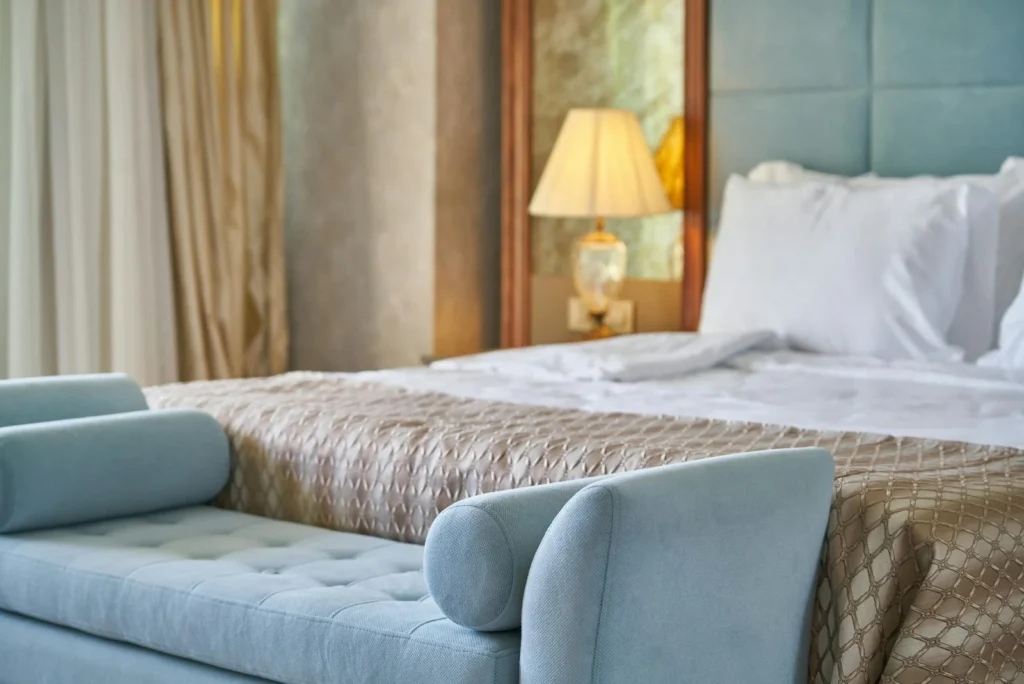 Light blue upholstered sofa positioned at the foot of a made bed
