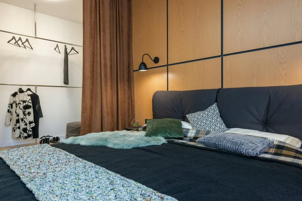 Twin bed frame with storage drawers in a compact bedroom with wood panel wall