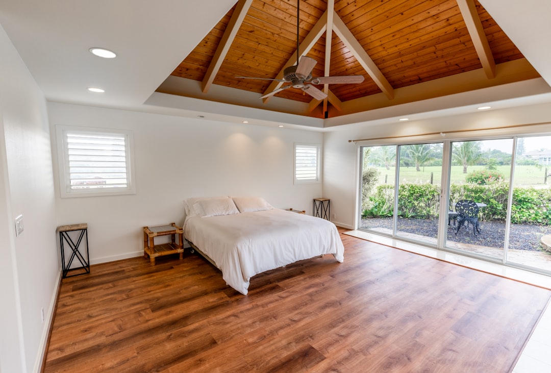 A latex mattress topper on a bed in a minimalist bedroom with natural light streaming through sheer curtains.]