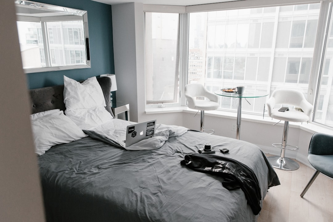 modern bedroom with sleek metal canopy bed next to a traditional wooden four poster bed