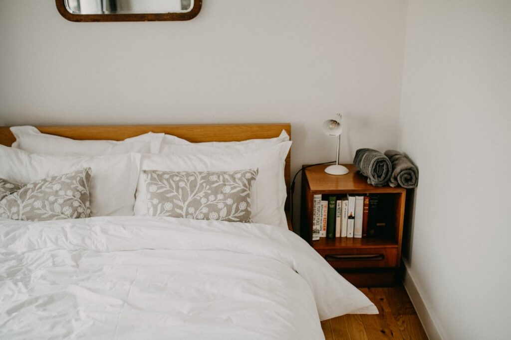 Tidy guest bedroom with white bedding and folded blankets where a rollaway bed can be set up for visitors
