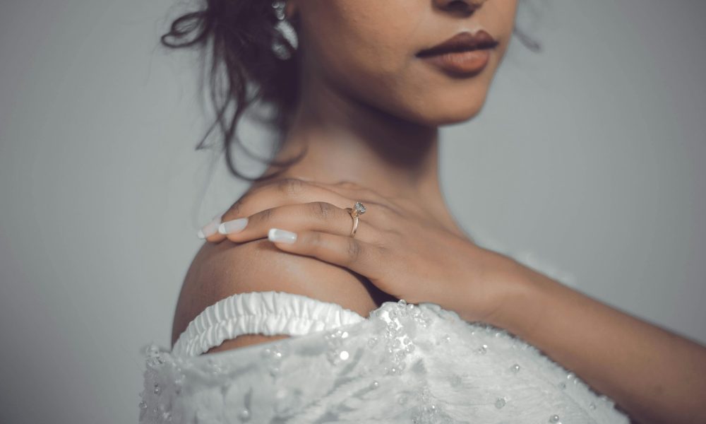 : Bride in white dress with engagement ring, evoking nuptial bedding ceremonies tradition.